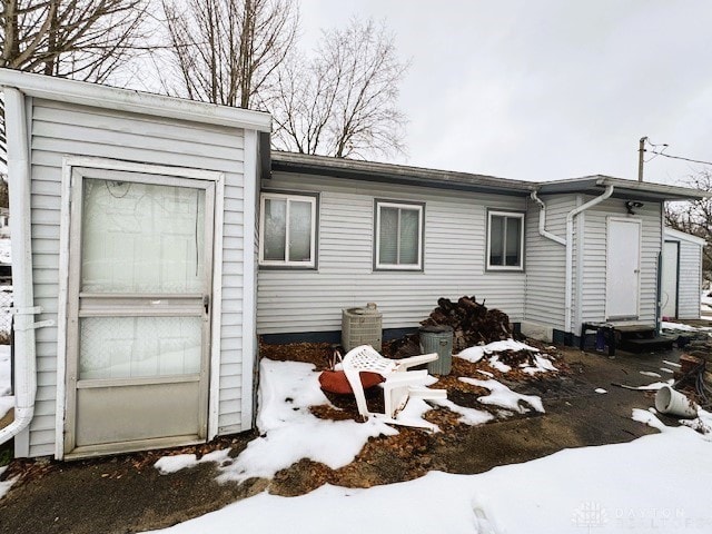 snow covered back of property with a garage