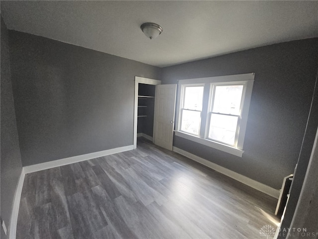 unfurnished bedroom with dark wood-type flooring and a closet