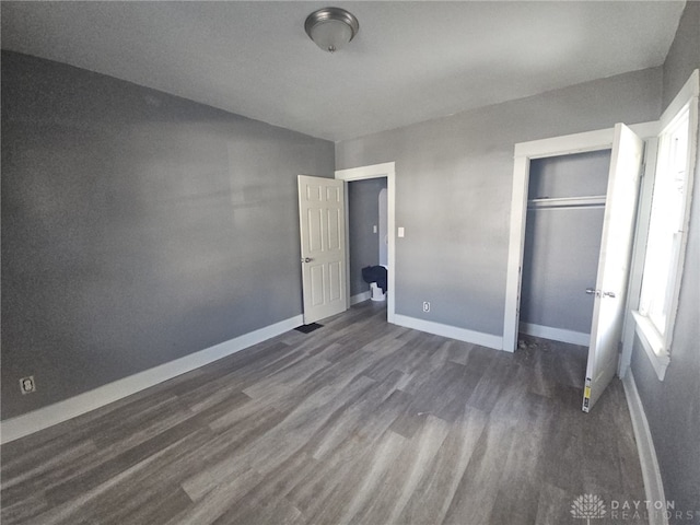 unfurnished bedroom with a closet and dark hardwood / wood-style floors