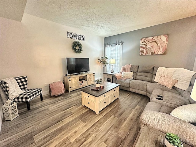 living room with a textured ceiling, wood finished floors, and baseboards