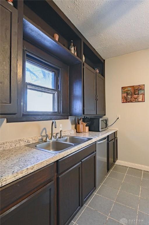 kitchen featuring dark tile patterned flooring, stainless steel appliances, a textured ceiling, light countertops, and a sink