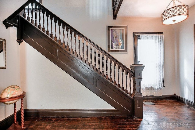 staircase with wood-type flooring, baseboards, and beam ceiling