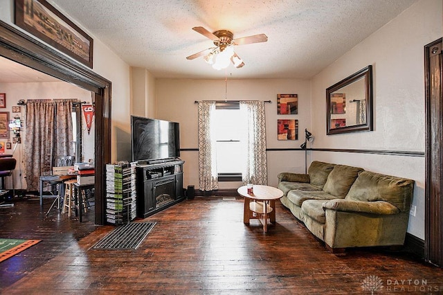 living room with ceiling fan, a textured ceiling, and wood-type flooring