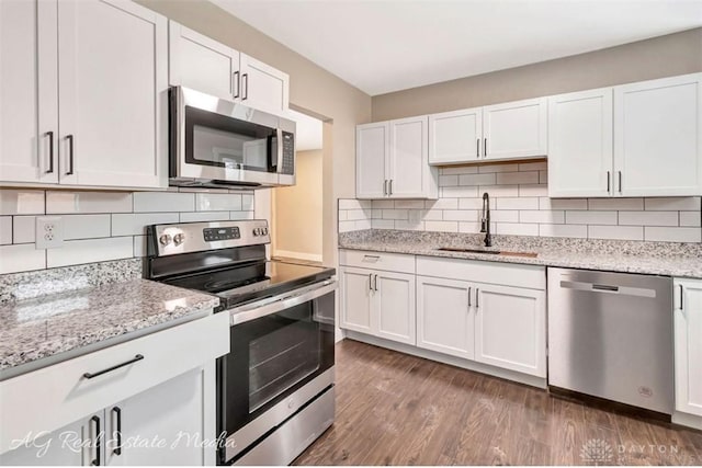 kitchen with dark wood-type flooring, appliances with stainless steel finishes, white cabinets, and sink