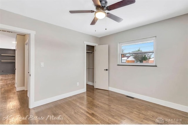 unfurnished bedroom featuring ceiling fan, a walk in closet, and light hardwood / wood-style flooring