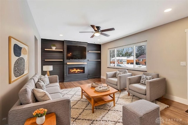 living room with light hardwood / wood-style floors, ceiling fan, and a fireplace