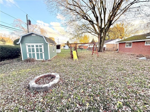 view of yard featuring a storage shed, a fire pit, and a playground