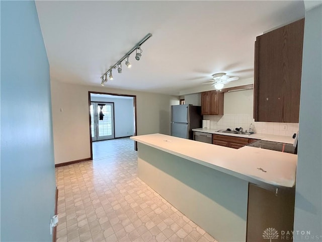 kitchen featuring kitchen peninsula, ceiling fan, appliances with stainless steel finishes, tasteful backsplash, and dark brown cabinets