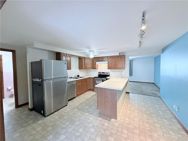 kitchen featuring appliances with stainless steel finishes, track lighting, sink, kitchen peninsula, and ceiling fan