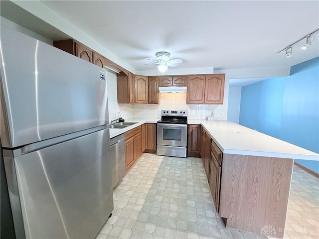 kitchen featuring kitchen peninsula, ceiling fan, stainless steel appliances, backsplash, and sink