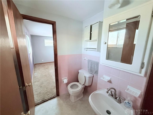 bathroom featuring toilet, tile walls, and sink