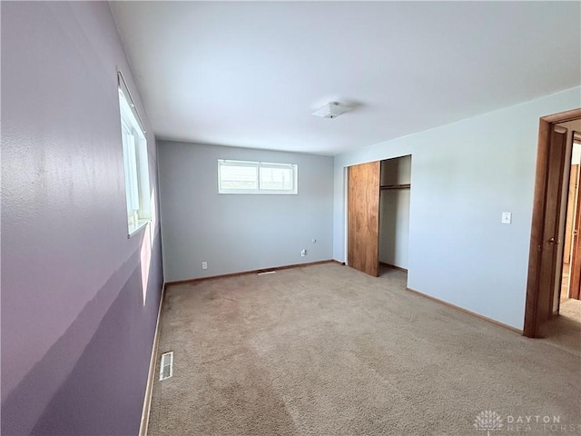 unfurnished bedroom featuring a closet and light carpet