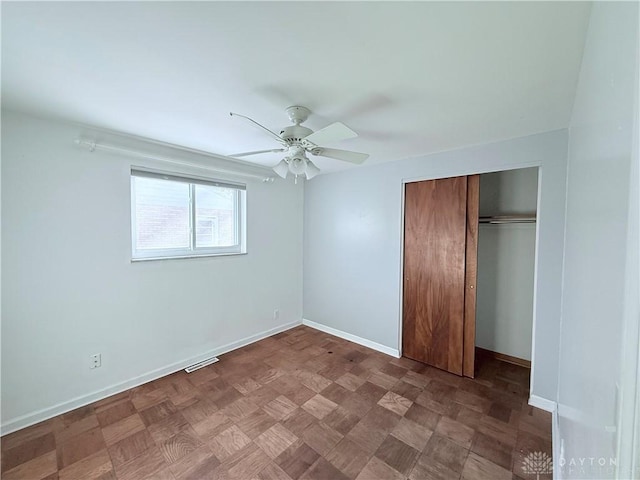 unfurnished bedroom with ceiling fan, a closet, and parquet flooring