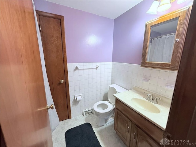 bathroom featuring toilet, vanity, and tile walls