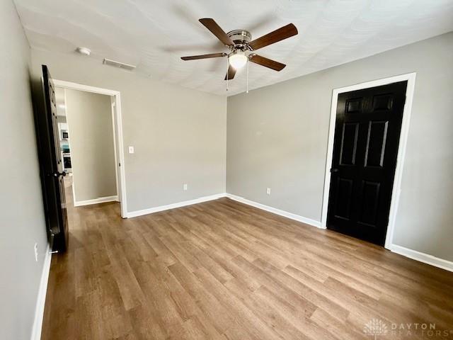 empty room with ceiling fan and light hardwood / wood-style flooring