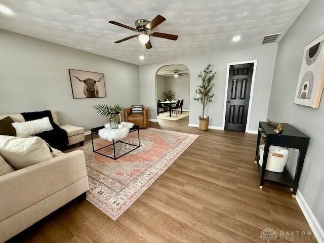 living room featuring a textured ceiling, ceiling fan, and hardwood / wood-style flooring