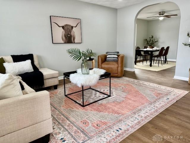 living room with dark wood-type flooring and ceiling fan