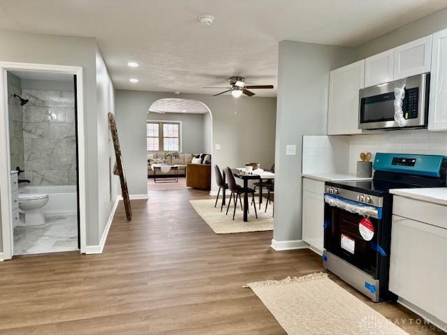 kitchen featuring ceiling fan, tasteful backsplash, light hardwood / wood-style floors, appliances with stainless steel finishes, and white cabinets