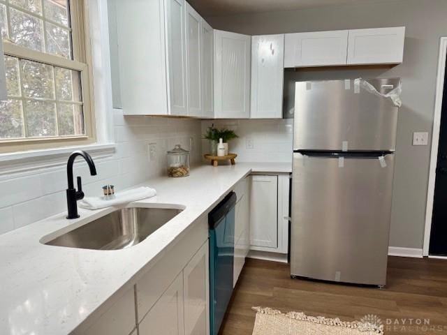 kitchen with white cabinetry, stainless steel fridge, backsplash, sink, and dishwashing machine