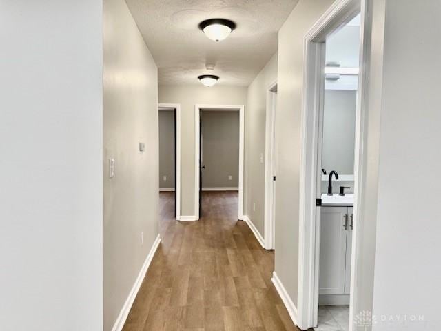 corridor with sink and light hardwood / wood-style flooring