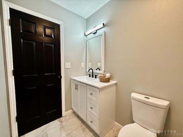 bathroom with toilet, a textured ceiling, and vanity