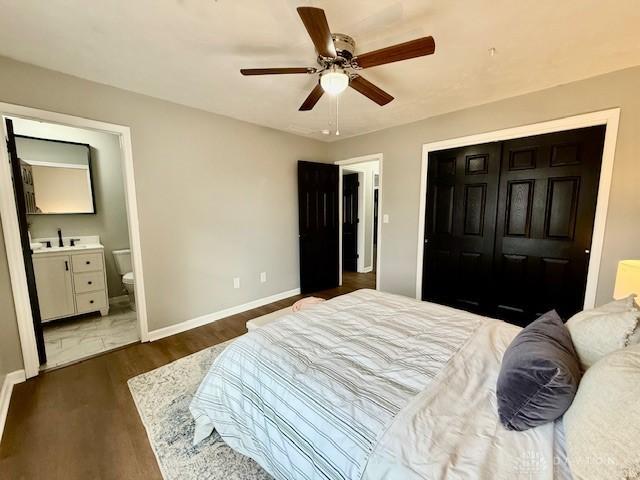 bedroom with ceiling fan, sink, dark hardwood / wood-style floors, and ensuite bath