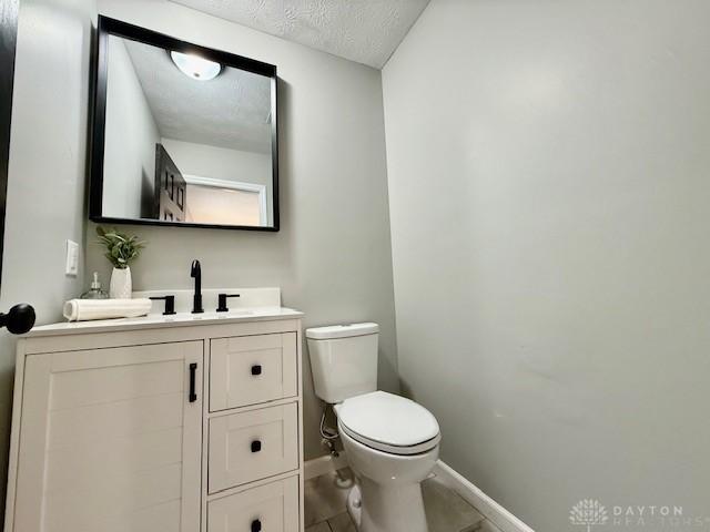 bathroom featuring a textured ceiling, toilet, and vanity