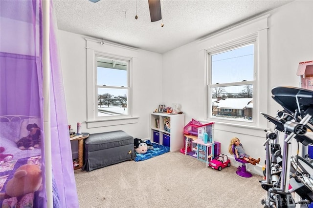 game room with ceiling fan, a textured ceiling, and carpet flooring