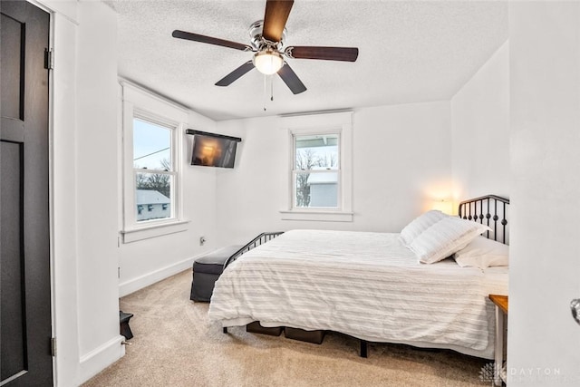 bedroom with a textured ceiling, ceiling fan, light colored carpet, and multiple windows