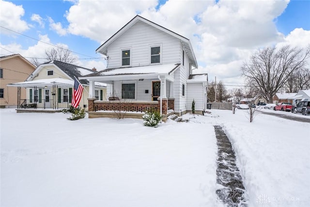 snow covered house featuring a porch