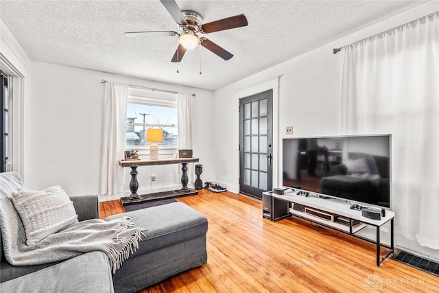 living room featuring ceiling fan, hardwood / wood-style floors, and a textured ceiling