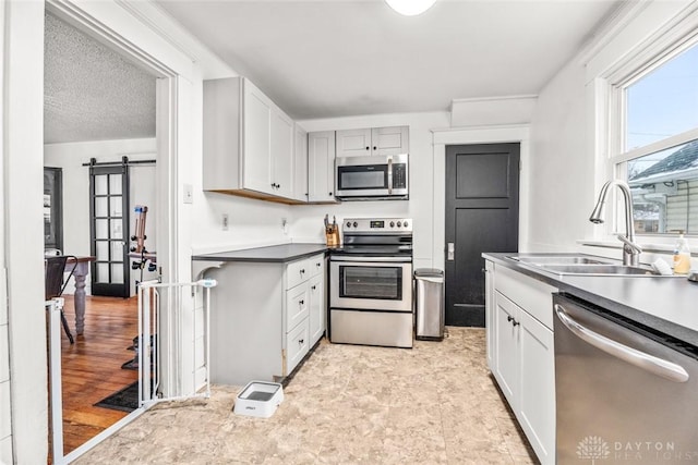 kitchen with a barn door, appliances with stainless steel finishes, sink, and a textured ceiling