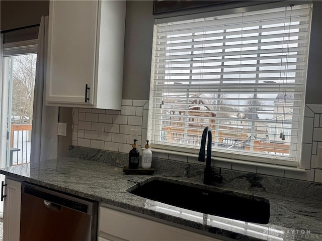 kitchen featuring dishwasher, stone counters, decorative backsplash, sink, and white cabinets