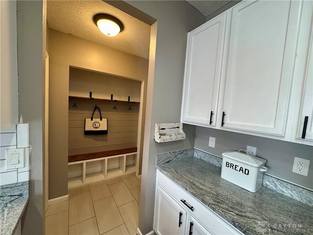 mudroom with a textured ceiling and light tile patterned floors