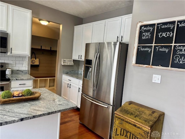 kitchen with tasteful backsplash, white cabinetry, light stone countertops, stainless steel appliances, and dark hardwood / wood-style flooring