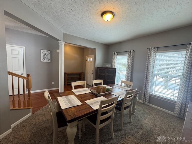 dining space with a textured ceiling, ornate columns, and carpet flooring