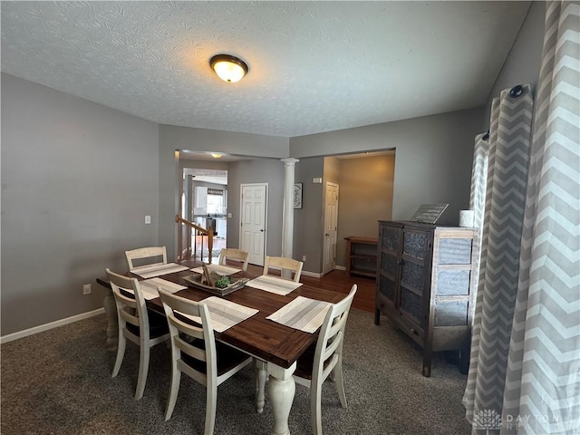 dining room featuring dark colored carpet, a textured ceiling, and decorative columns