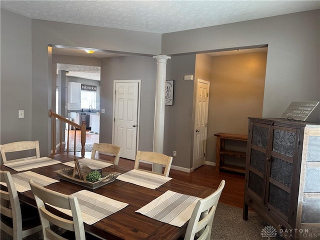 dining area featuring a textured ceiling, ornate columns, wood-type flooring, and sink