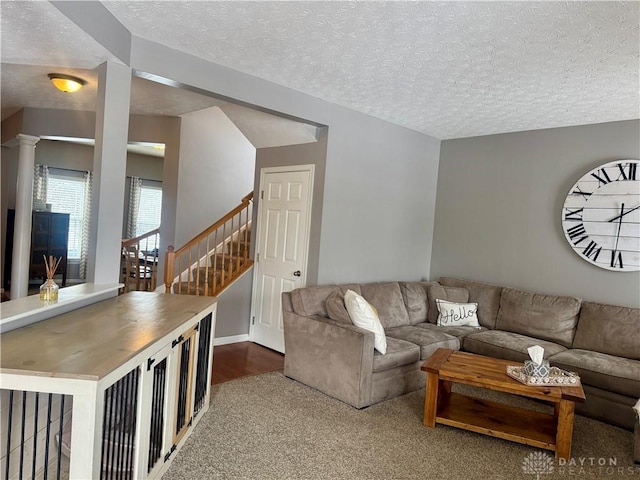 carpeted living room with decorative columns and a textured ceiling