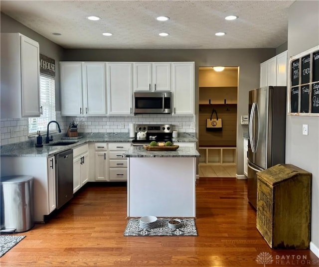 kitchen featuring light stone countertops, a textured ceiling, white cabinets, stainless steel appliances, and sink