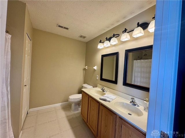 bathroom with toilet, vanity, and a textured ceiling