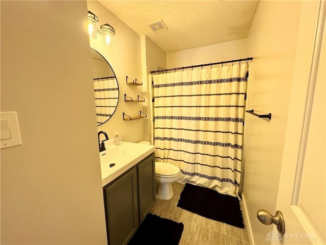 bathroom with toilet, vanity, a shower with shower curtain, and a textured ceiling