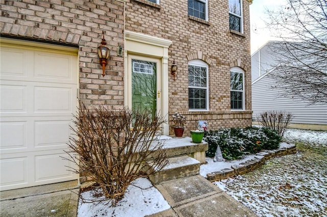 snow covered property entrance featuring a garage