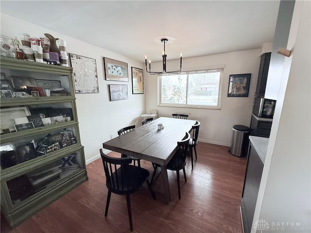 dining area featuring a notable chandelier, dark wood-type flooring, and baseboards