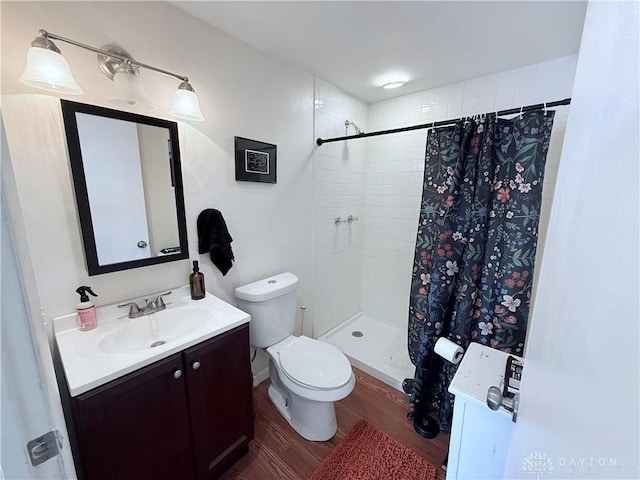 full bath featuring a shower stall, toilet, vanity, and wood finished floors