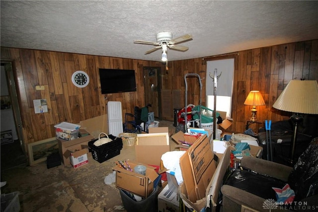 interior space with ceiling fan, wood walls, and a textured ceiling