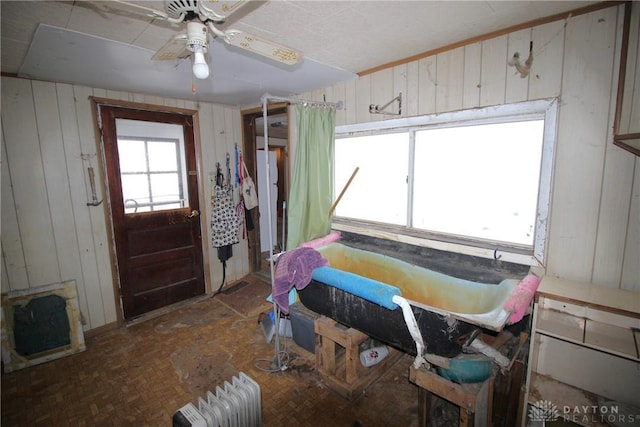 interior space featuring ceiling fan and wood walls