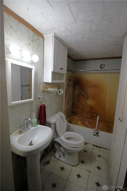 bathroom with toilet, crown molding, and  shower combination