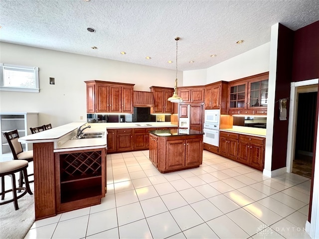 kitchen with pendant lighting, sink, a kitchen breakfast bar, kitchen peninsula, and white appliances