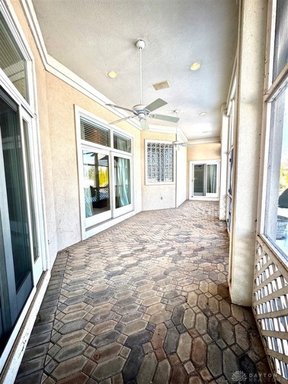 unfurnished sunroom featuring ceiling fan